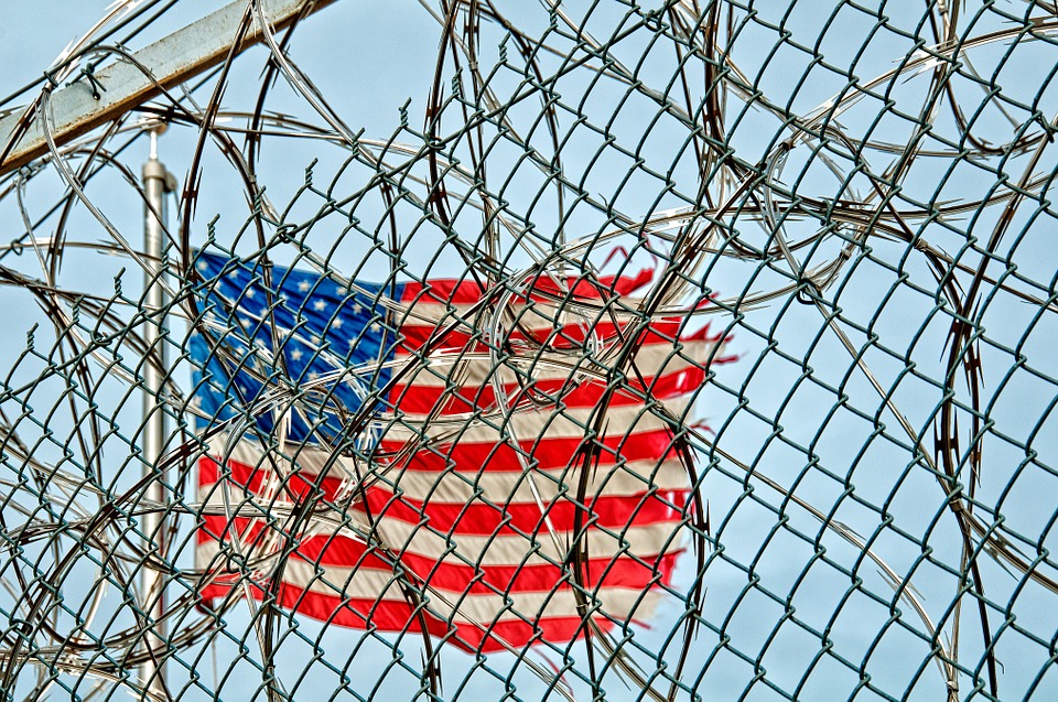 photo of prison fence with american flag behind it